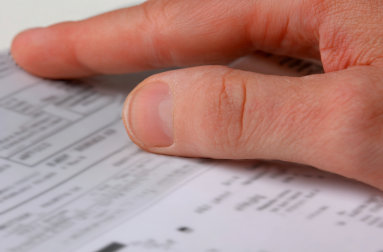 A hands rest over a restaurant electrical bill that is lower than normal because they started using Frylow